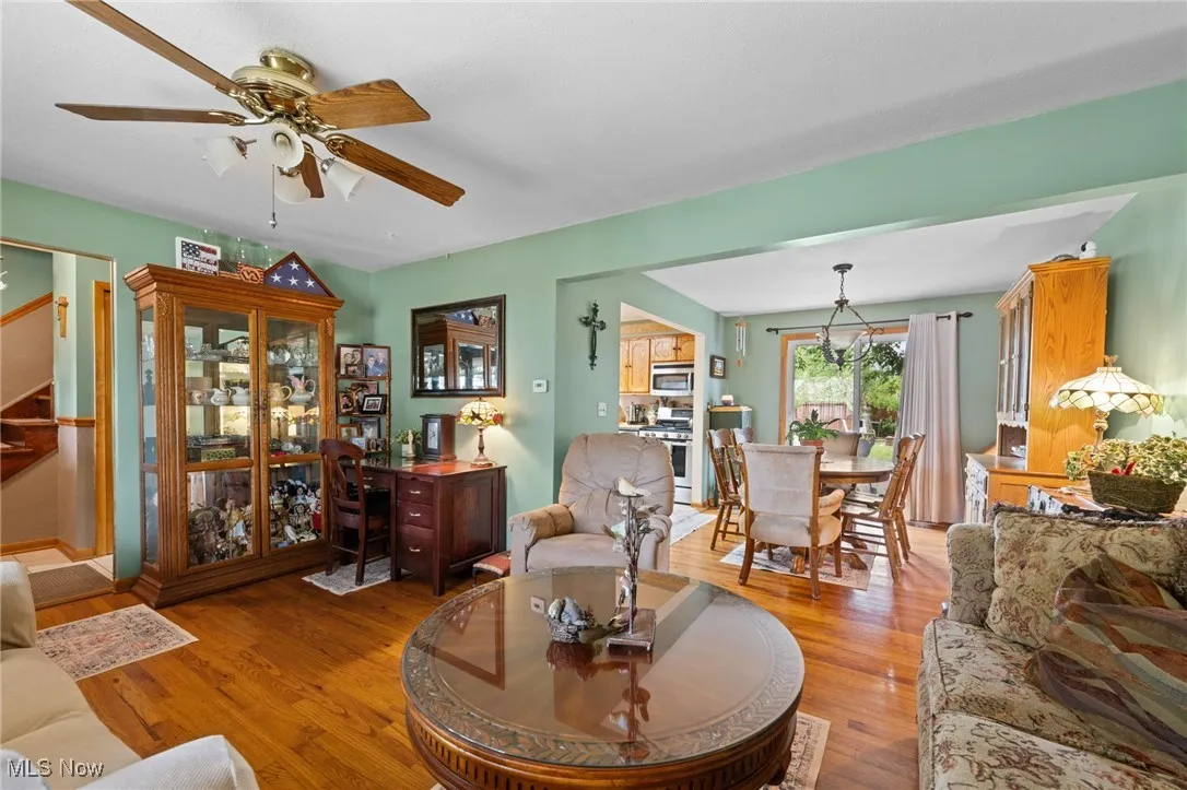 Living room with a ceiling fan, light wood finished floors, and stairs