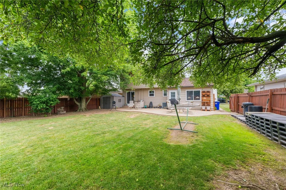 Fenced backyard featuring a shed and a patio area