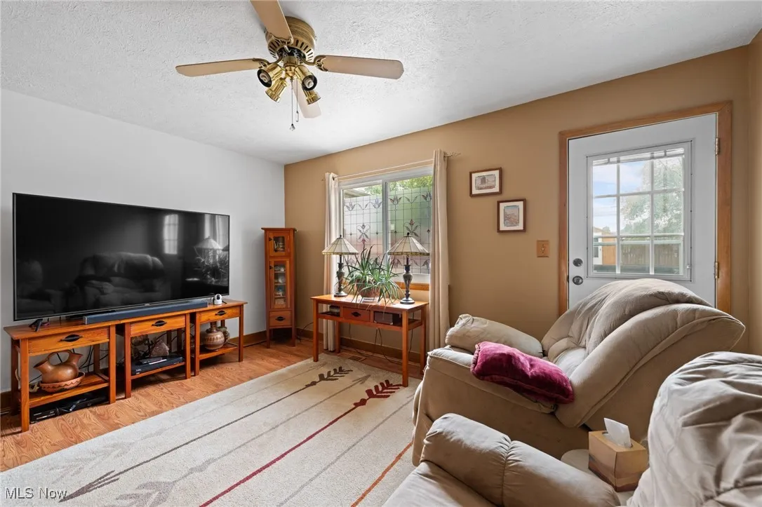 Living room featuring wood finished floors, a textured ceiling, and a ceiling fan
