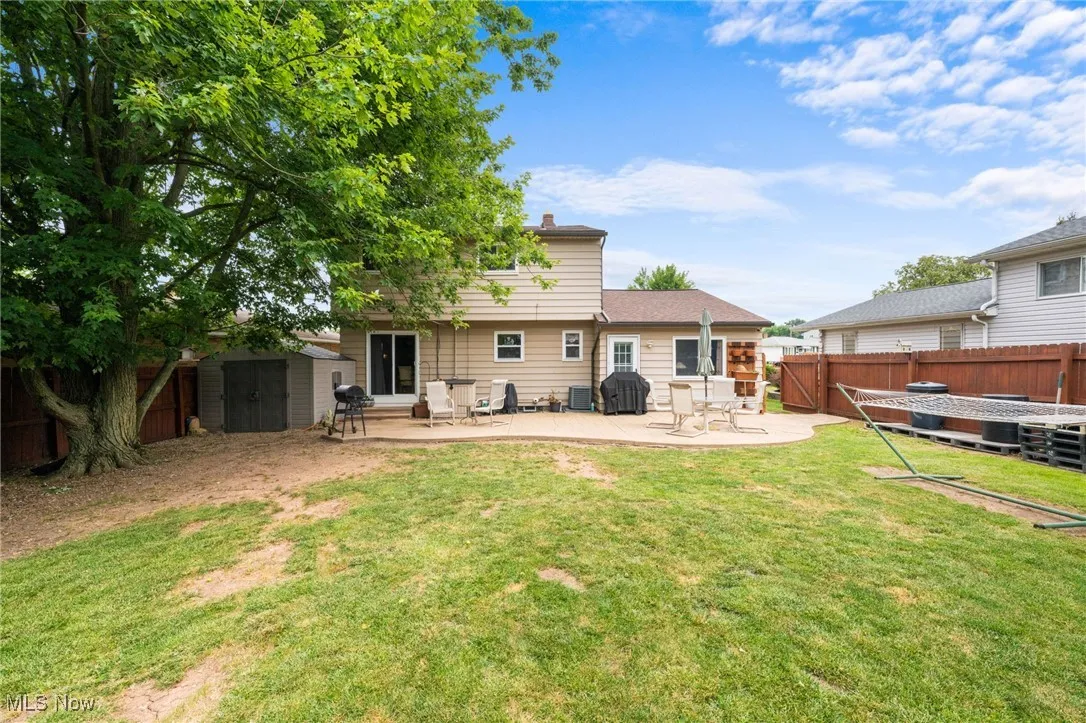 Rear view of house featuring a storage unit, a fenced backyard, and a patio