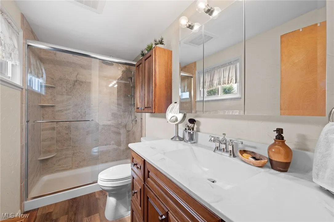 Bathroom with vanity, a shower stall, and wood finished floors
