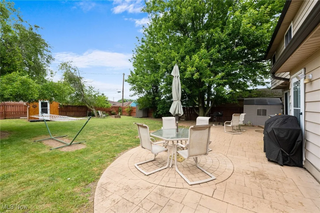 Fenced backyard with a shed, a patio area, a grill, and outdoor dining space