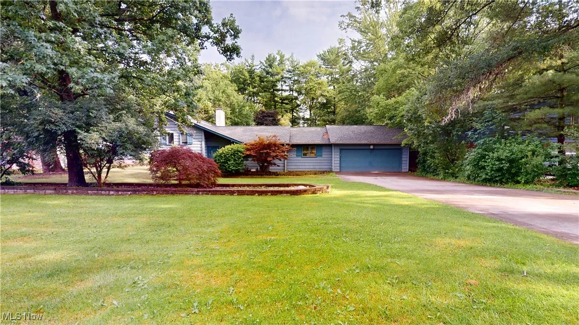 View of front facade with concrete driveway, an attached garage, a front yard, and a chimney