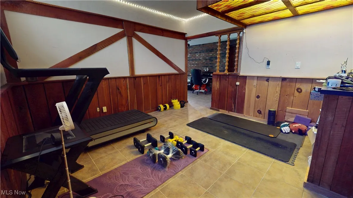 Basement Workout room with wainscoting, wood walls, and tile patterned flooring