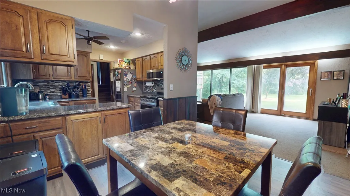Kitchen with stainless steel appliances, a ceiling fan, decorative backsplash, brown cabinetry, and recessed lighting