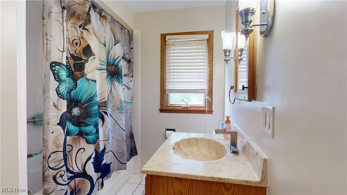 Main Bathroom featuring vanity, shower / bath combo with shower curtain, and tile patterned floors