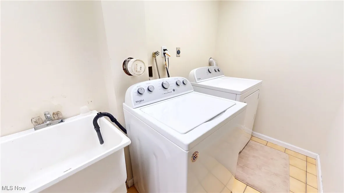 Washroom with separate washer and dryer and light tile patterned floors