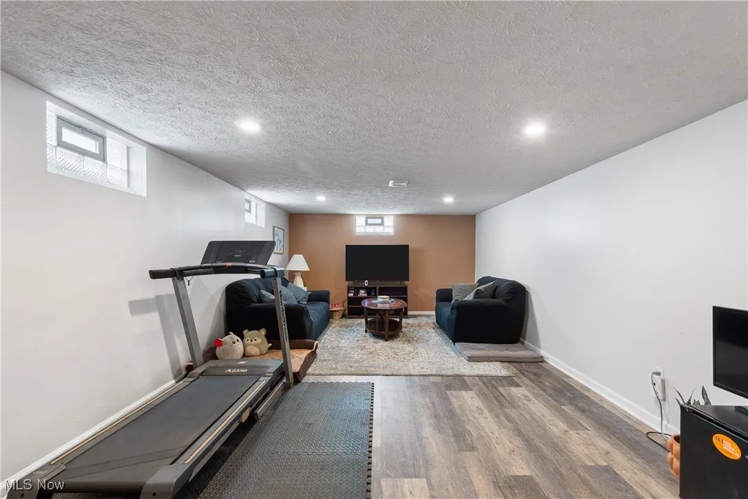Workout area featuring wood finished floors, recessed lighting, and a textured ceiling