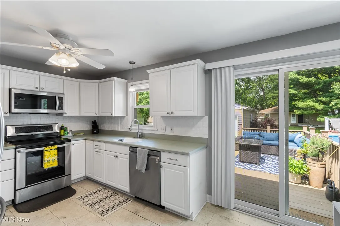 Kitchen featuring appliances with stainless steel finishes, backsplash, white cabinets, and light countertops
