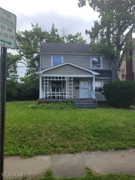 View of front of property featuring a front yard, covered porch, and a chimney
