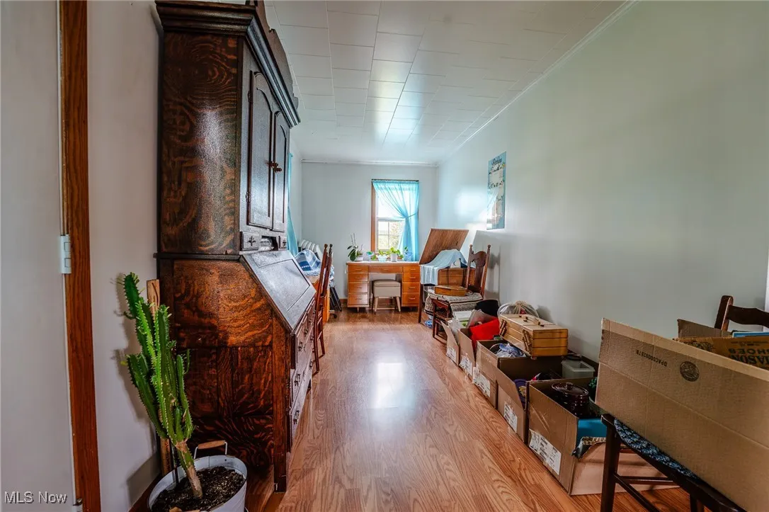 Hall with light wood-style flooring and ornamental molding