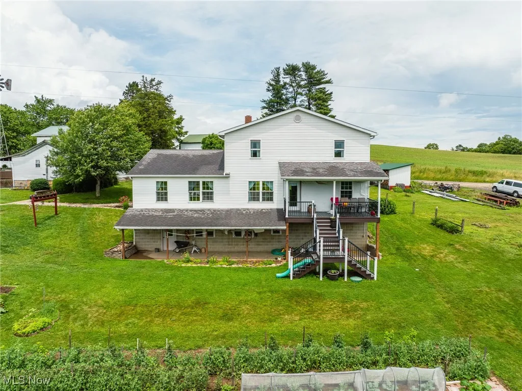 Rear view of house featuring stairway, a lawn, a wooden deck, a shingled roof, and a patio area