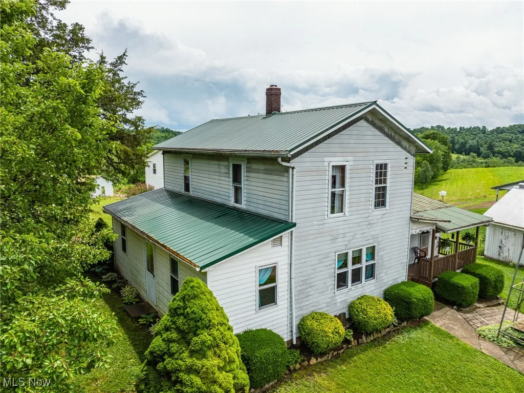 Back of house featuring a metal roof, a chimney, a lawn, and a wooden deck