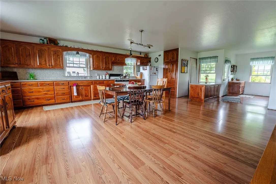 Kitchen featuring freestanding refrigerator, light wood finished floors, brown cabinetry, and backsplash