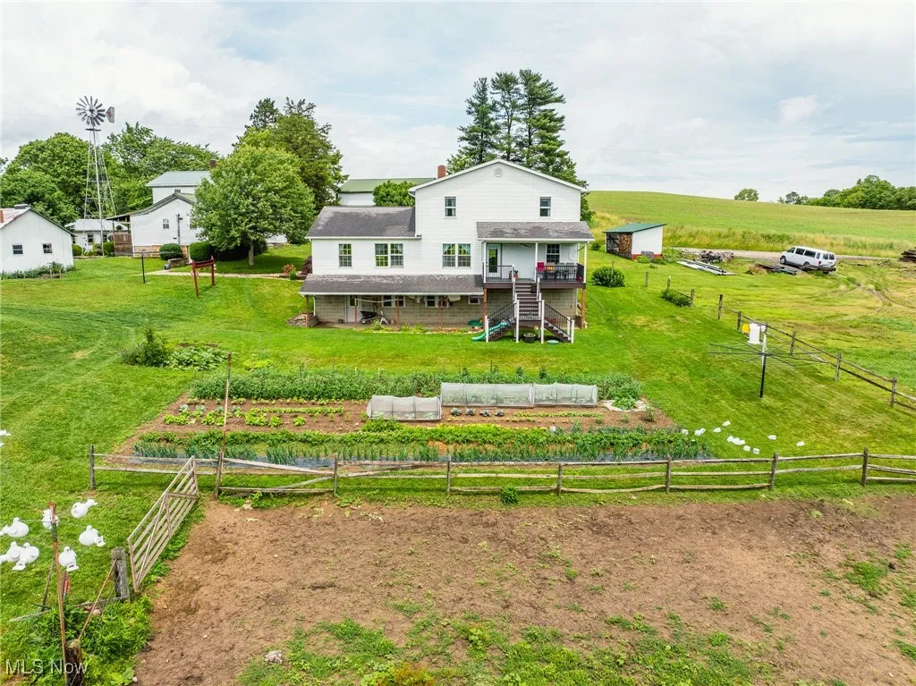Back of house with stairway, a vegetable garden, a wooden deck, and a view of countryside