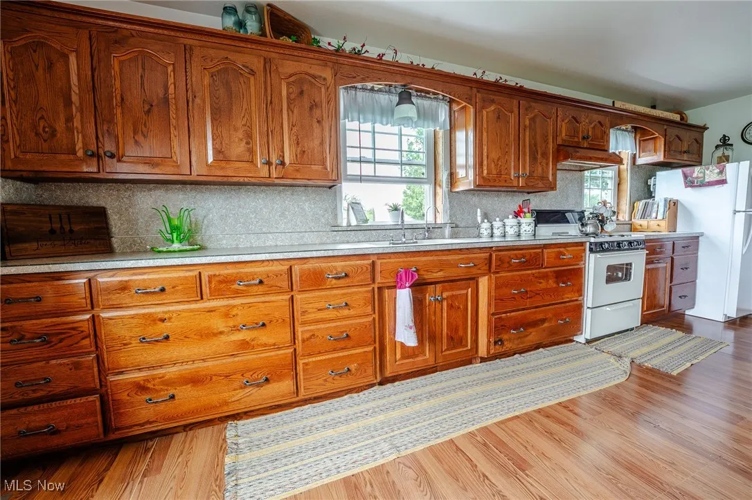 Kitchen with white appliances, light countertops, decorative backsplash, and healthy amount of natural light
