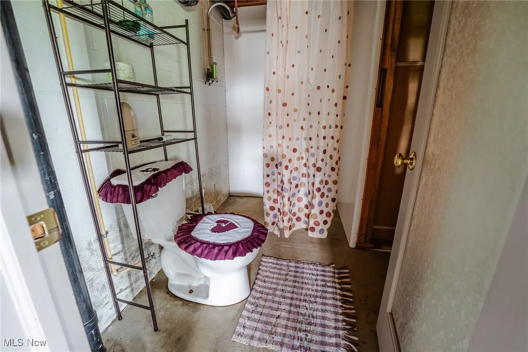 Bathroom with a shower with curtain and concrete flooring
