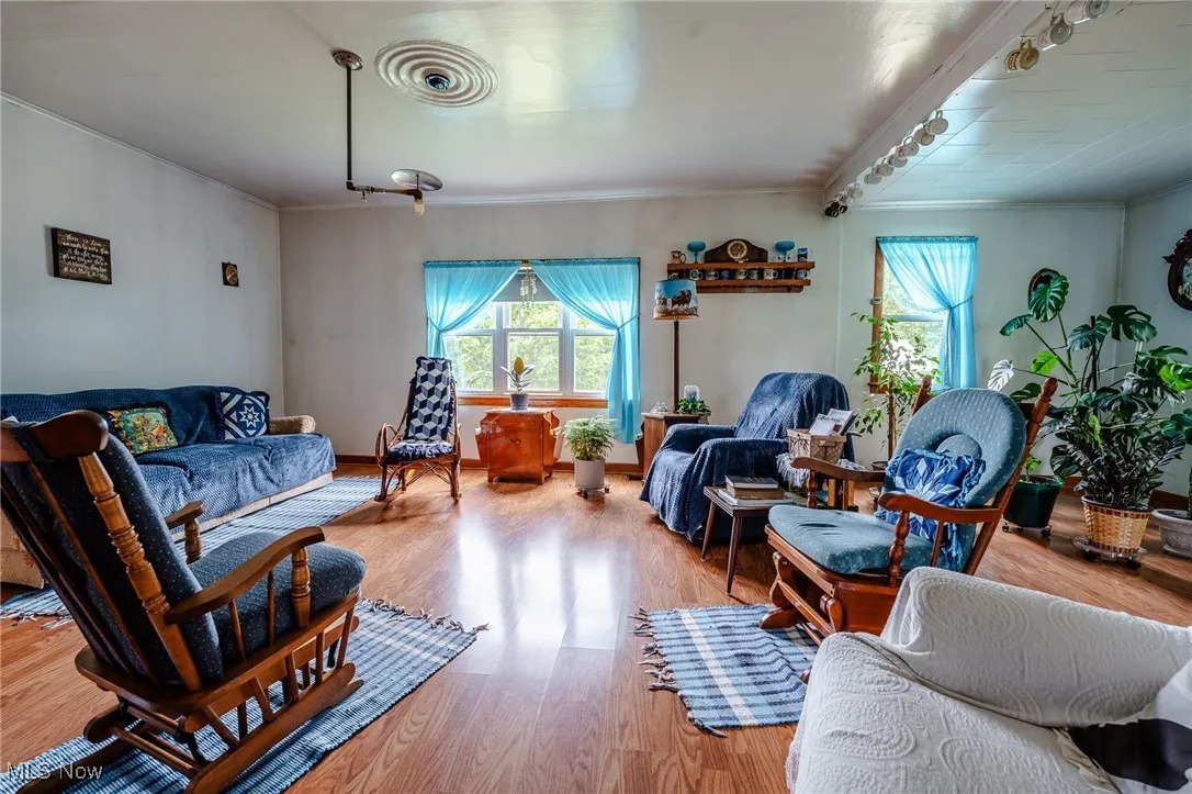 Living room with ornamental molding, healthy amount of natural light, and wood finished floors