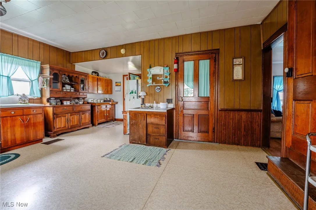 Kitchen featuring brown cabinets, wooden walls, open shelves, and light countertops