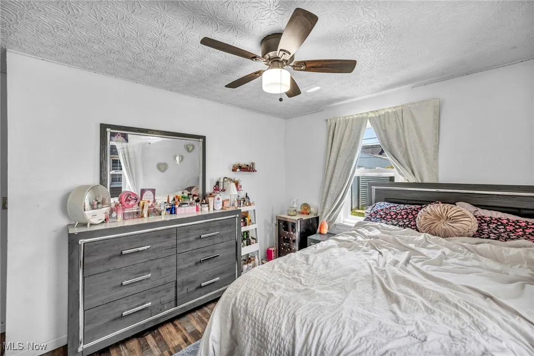 Bedroom featuring dark wood finished floors, a textured ceiling, and a ceiling fan