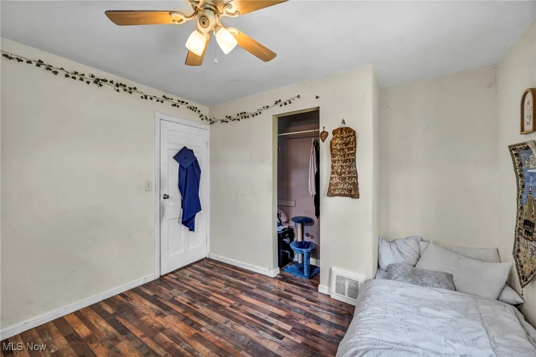 Bedroom featuring dark wood finished floors, a ceiling fan, and a closet