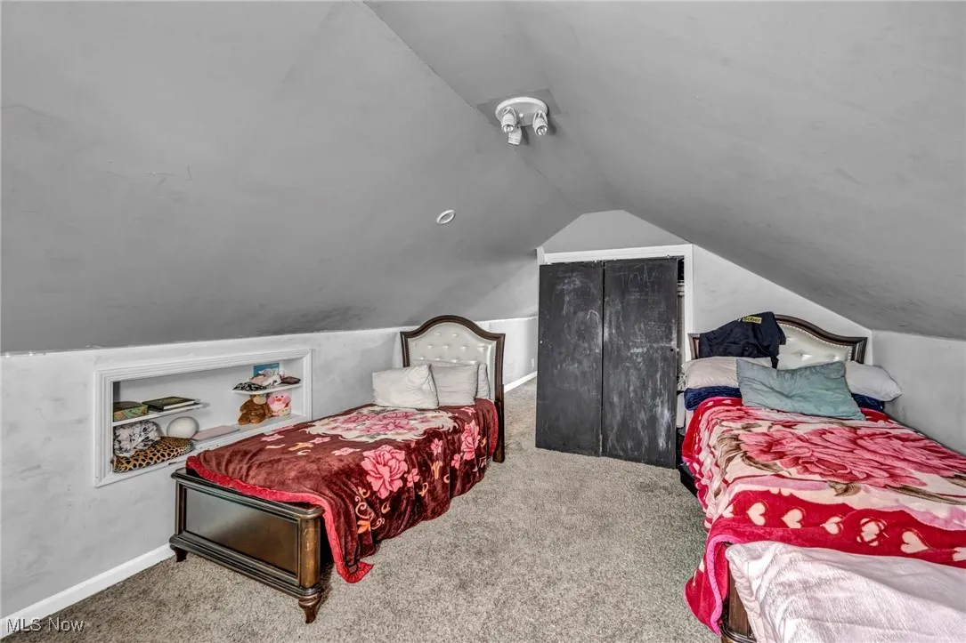 Carpeted bedroom featuring lofted ceiling and baseboards