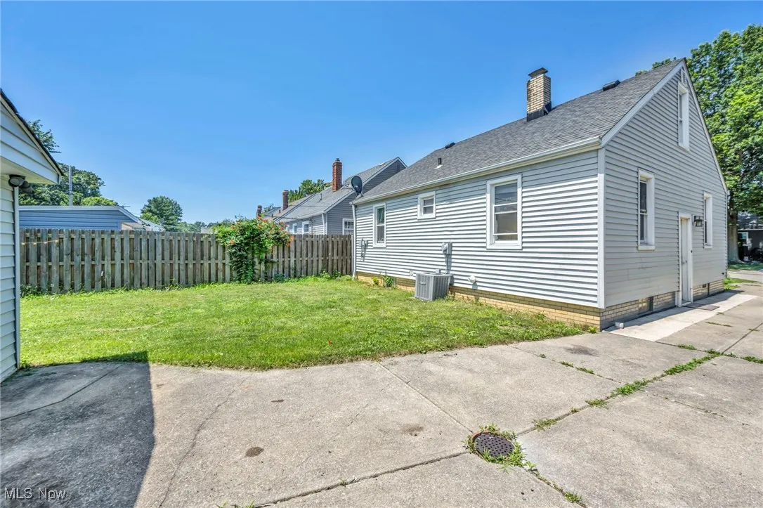 Rear view of house with a shingled roof, a chimney, and a patio