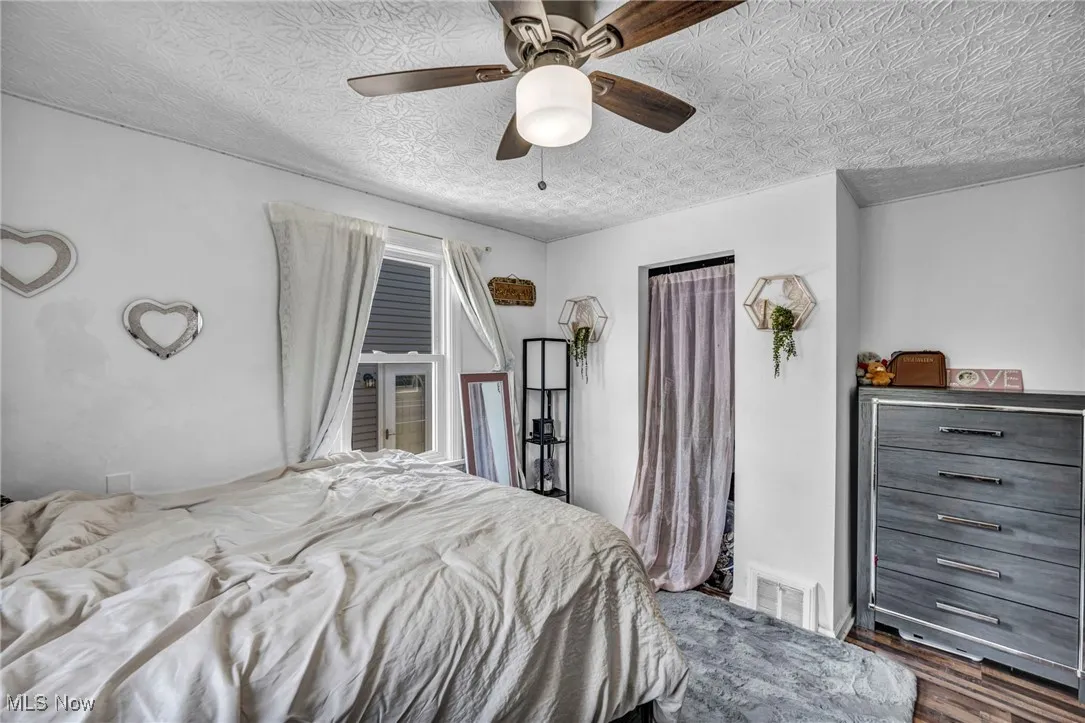 Bedroom with dark wood-style flooring, a textured ceiling, and ceiling fan