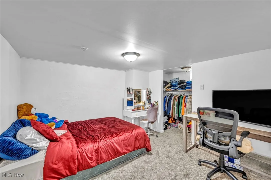 Carpeted bedroom featuring a desk and a closet