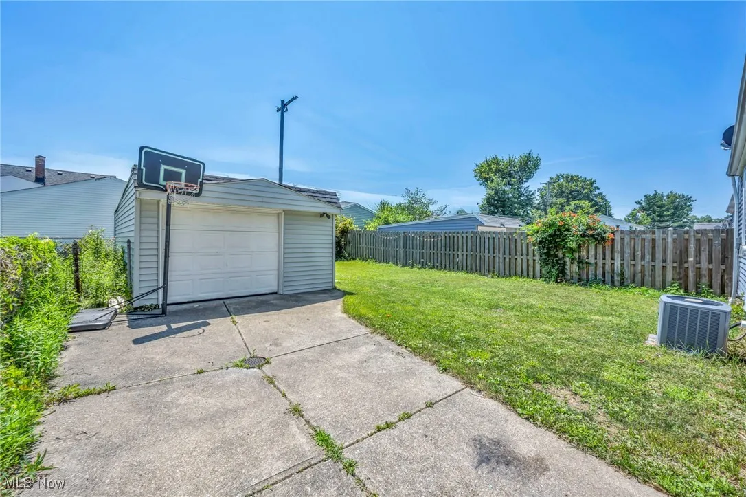 View of yard featuring an outdoor structure, concrete driveway, and a garage