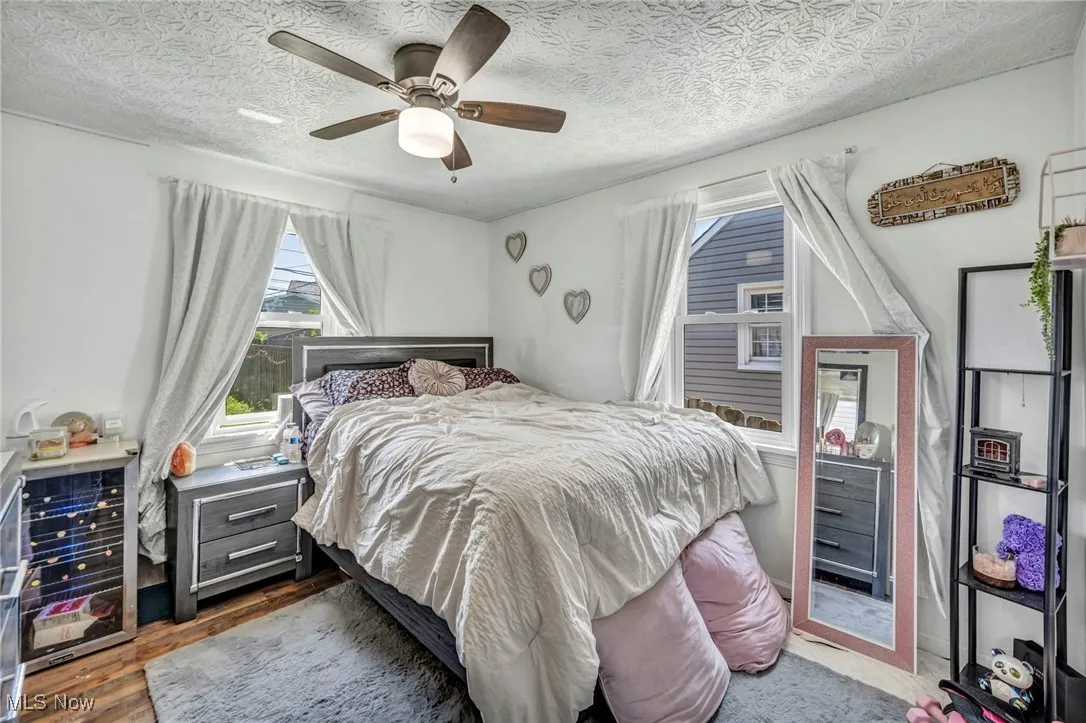 Bedroom with wood finished floors, ceiling fan, and a textured ceiling