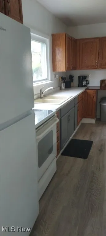 Kitchen featuring white appliances, light wood-type flooring, light countertops, and brown cabinets