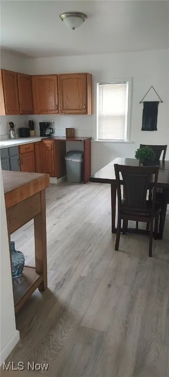 Kitchen with light wood-style flooring, brown cabinets, and light countertops