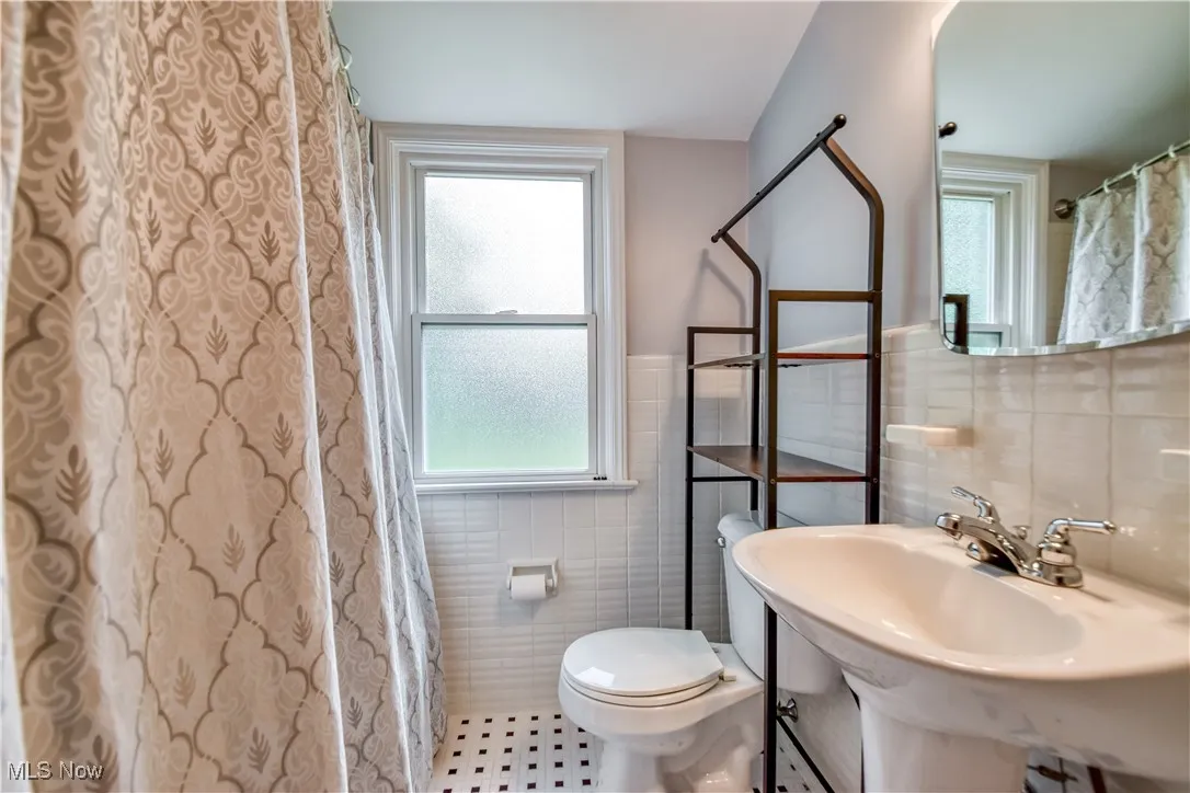 Bathroom with tile walls, tile patterned floors, and a wainscoted wall