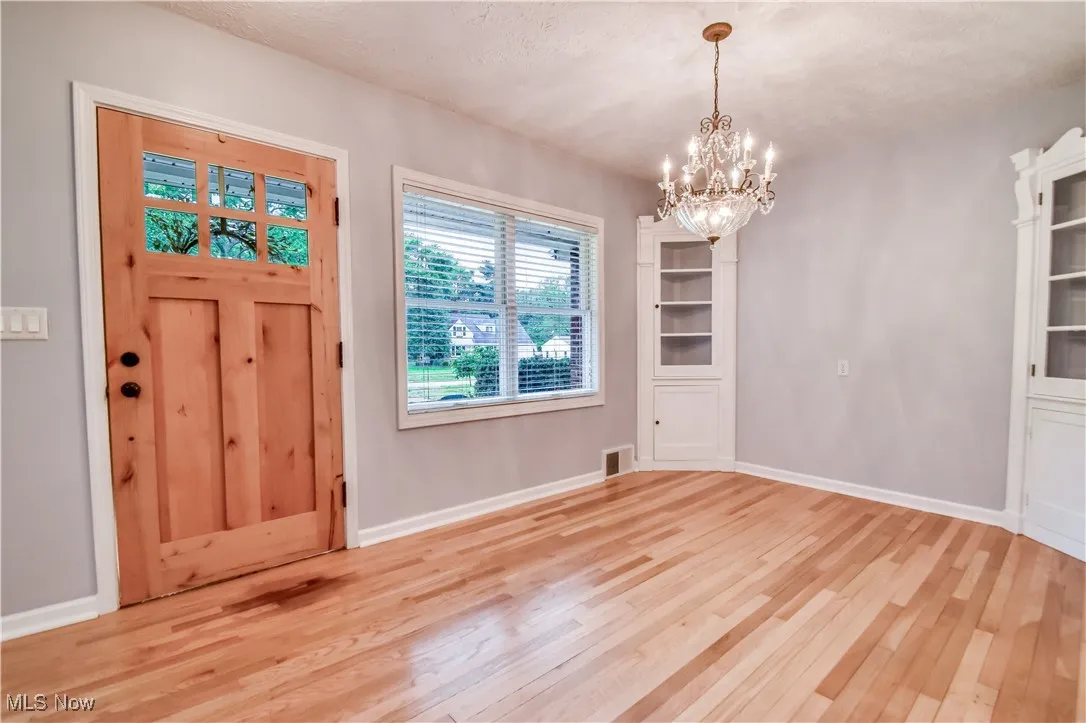 Foyer entrance with light wood-type flooring and a chandelier