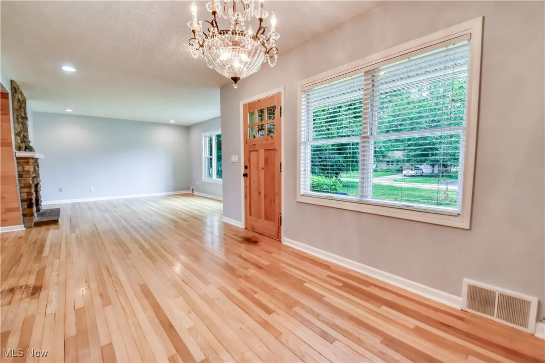 Unfurnished living room featuring hardwood / wood-style floors, a chandelier, a fireplace, and recessed lighting