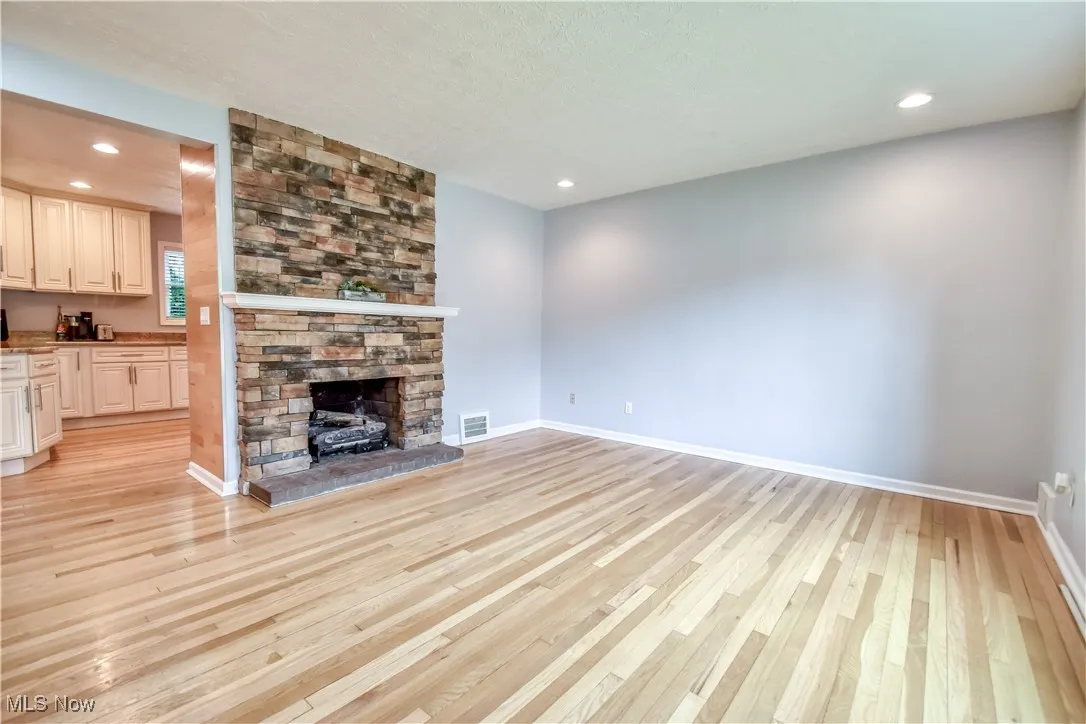 Unfurnished living room featuring light wood-type flooring, a fireplace, and recessed lighting