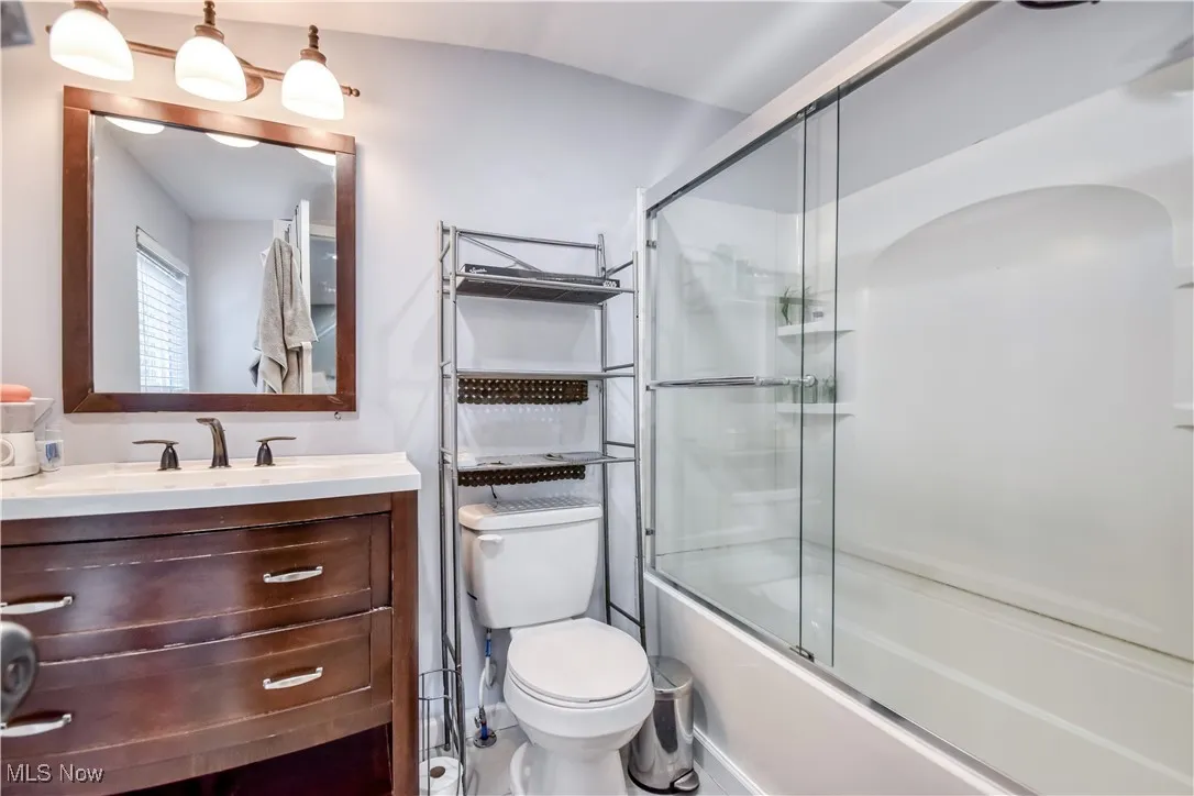 Full bath with vanity and bath / shower combo with glass door