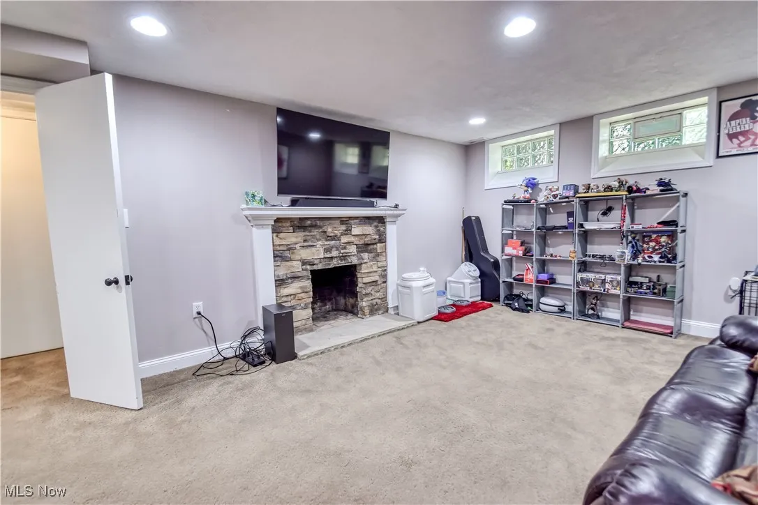 Carpeted living area with recessed lighting and a stone fireplace
