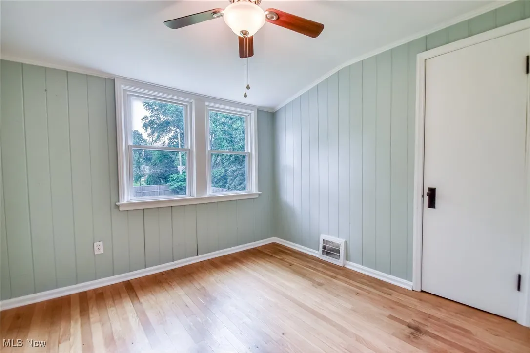 Unfurnished room with wood finished floors, a ceiling fan, and ornamental molding