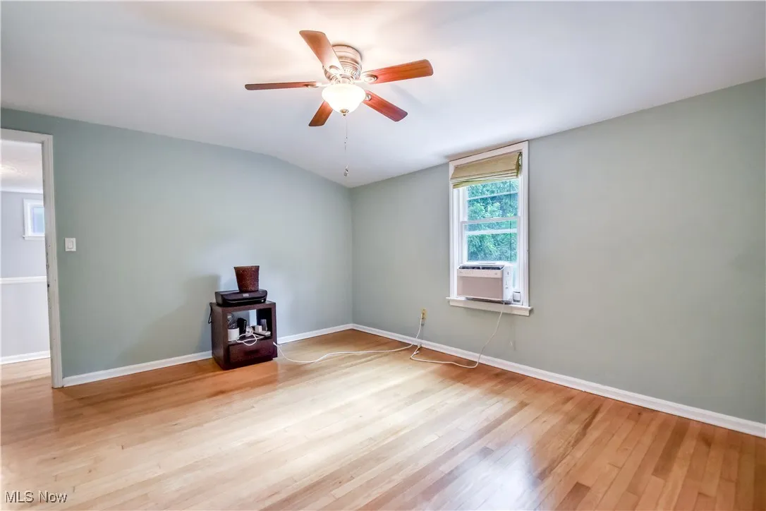 Spare room featuring wood finished floors, ceiling fan, vaulted ceiling, and cooling unit
