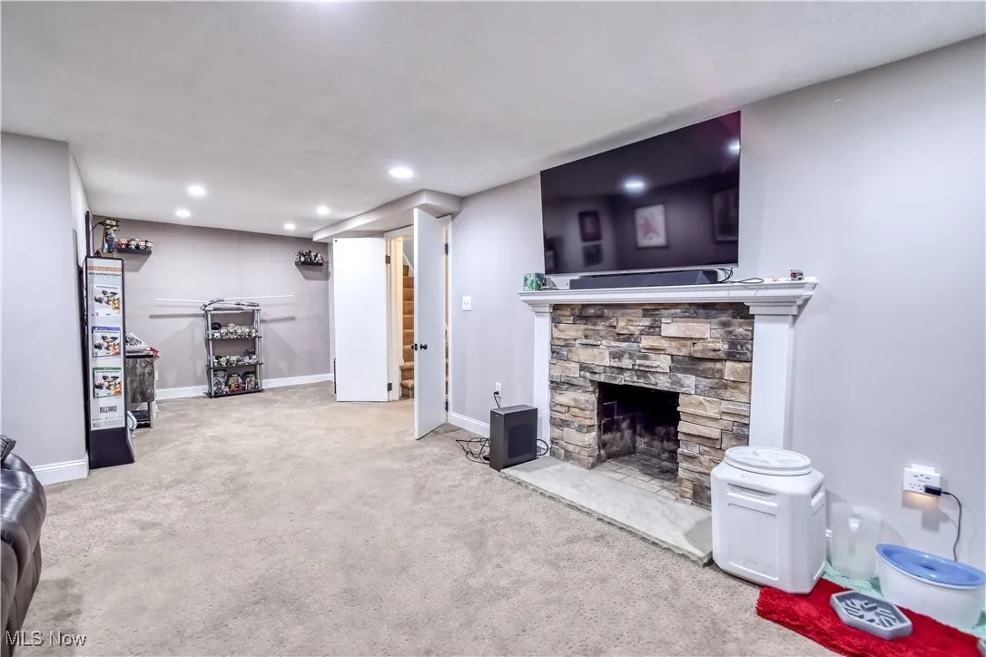 Living room featuring carpet floors, a stone fireplace, and recessed lighting