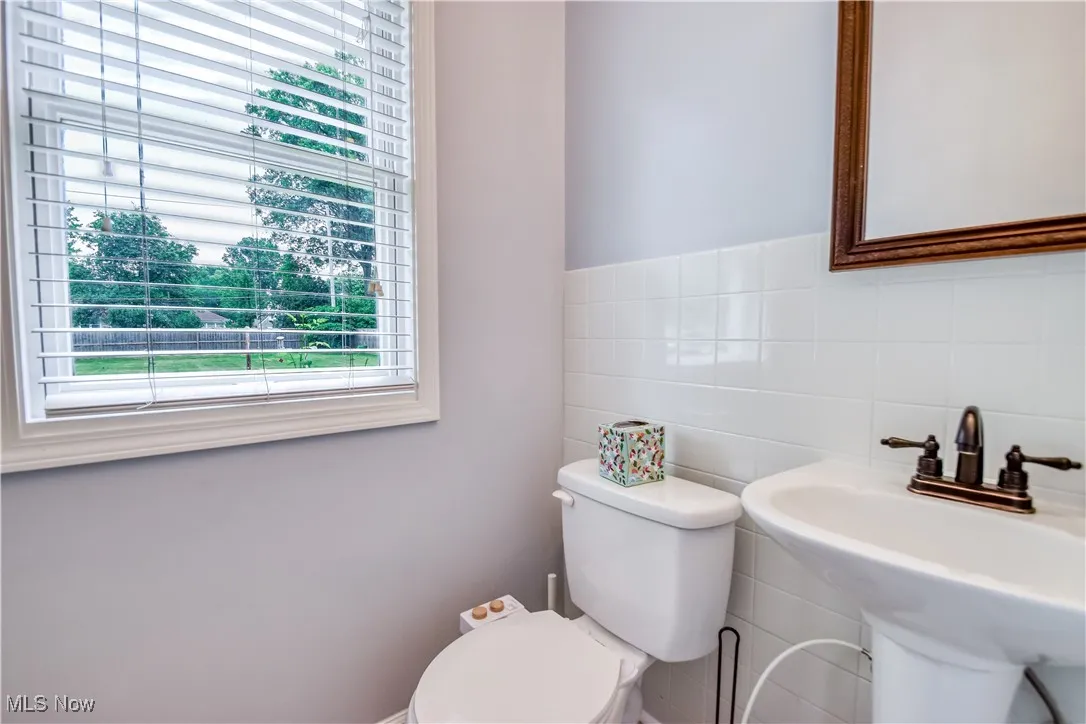 Bathroom with toilet and tile walls
