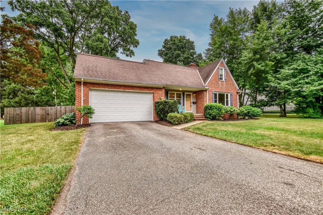 View of front facade featuring asphalt driveway, brick siding, a garage, and roof with shingles