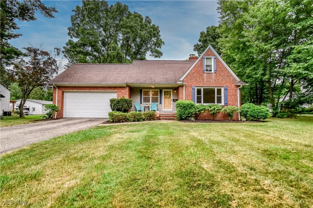 View of front facade with brick siding, driveway, an attached garage, and a front lawn