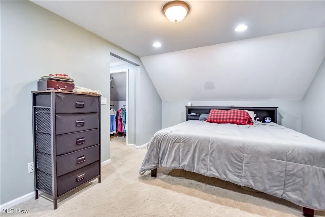 Bedroom featuring vaulted ceiling, light colored carpet, and recessed lighting