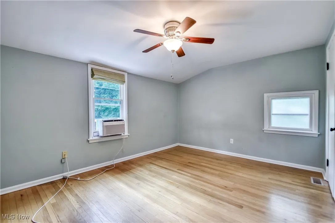 Spare room with cooling unit, wood-type flooring, and ceiling fan