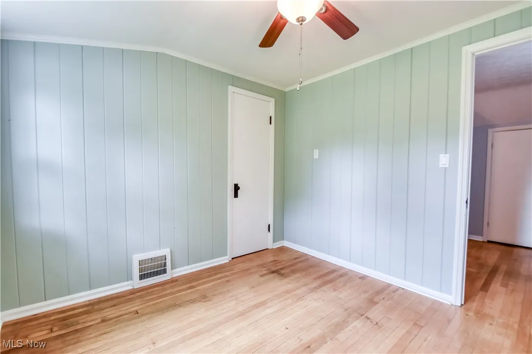 Unfurnished room with light wood-type flooring, ceiling fan, and crown molding