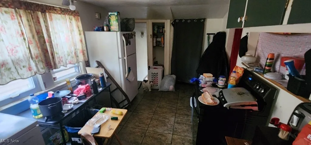 Kitchen with freestanding refrigerator, plenty of natural light, and dark tile patterned flooring