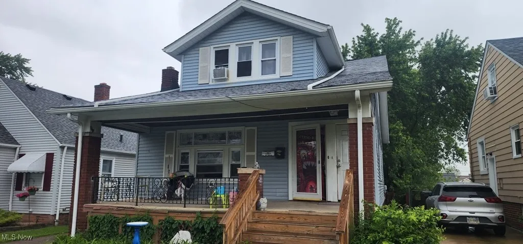 View of front of home featuring covered porch, a chimney, and brick siding